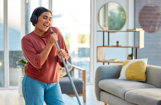 young woman singing into mophandle while spring cleaning