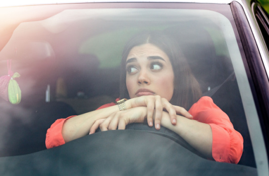 Worried young woman sits in her car