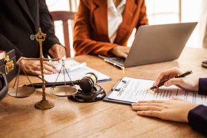 Legal professionals review and sign paperwork with a gavel and scales of justice on the table, illustrating the legal steps that may follow a speeding ticket in Georgia.