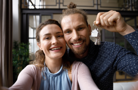 Young couple smiling dangling keys to new rental unit