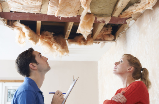 claims adjuster and home owner look at damage in roof