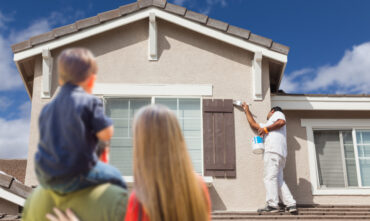 Young family watches as painters improve curb appeal of home before selling