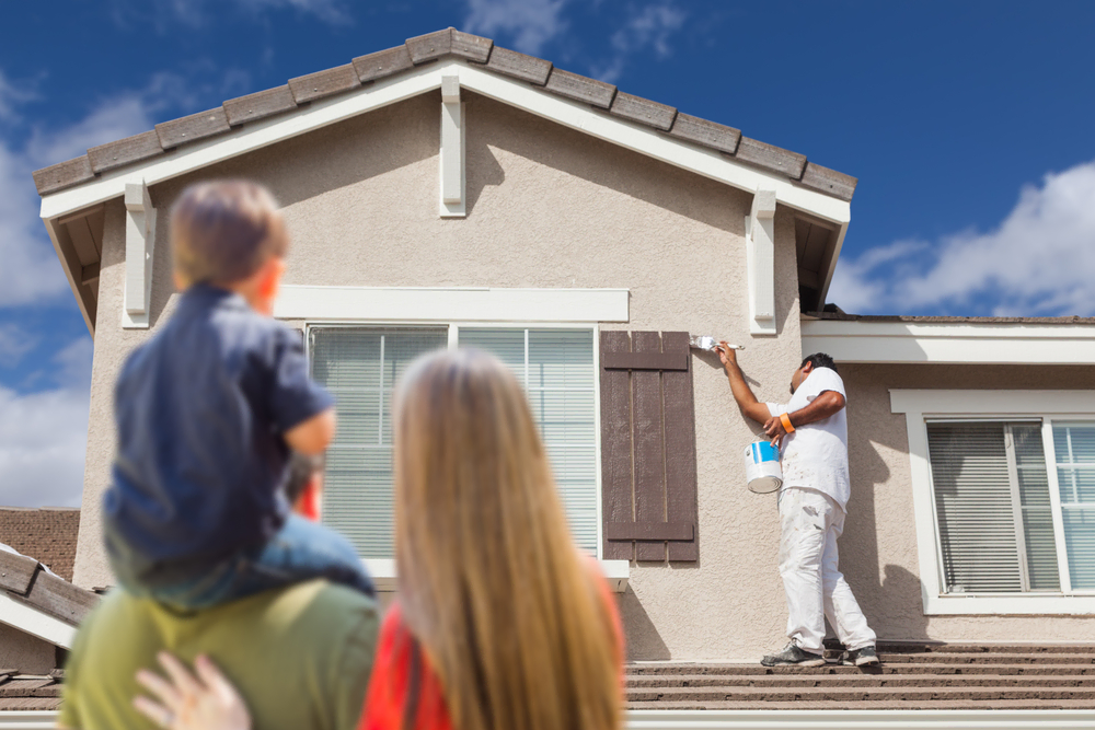 Young family watches as painters improve curb appeal of home before selling