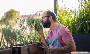 Hipster man works with his plants on his apartment balcony