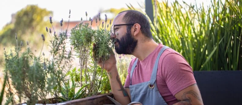 Hipster man works with his plants on his apartment balcony