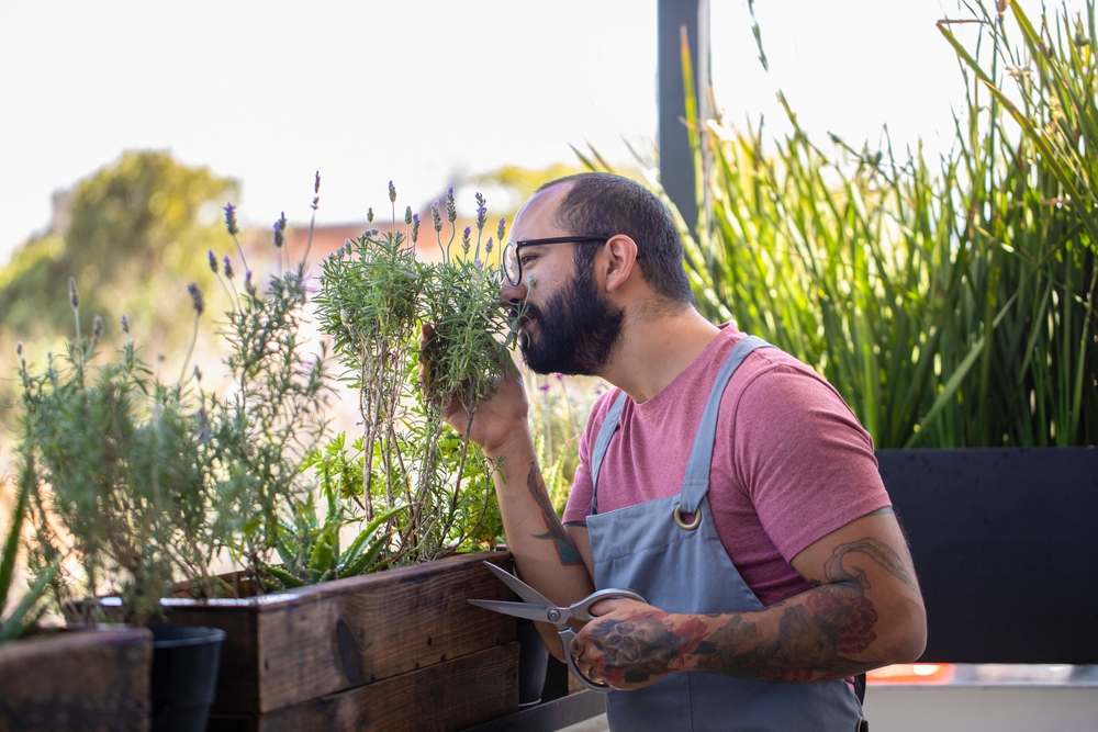 Hipster man works with his plants on his apartment balcony
