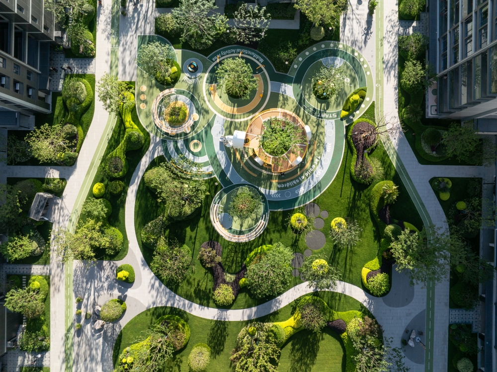 Aerial view of a landscaped apartment garden with walking paths, trees, and green spaces.
