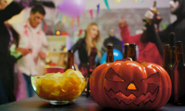 Scary pumpkin in forefront with halloween party in background