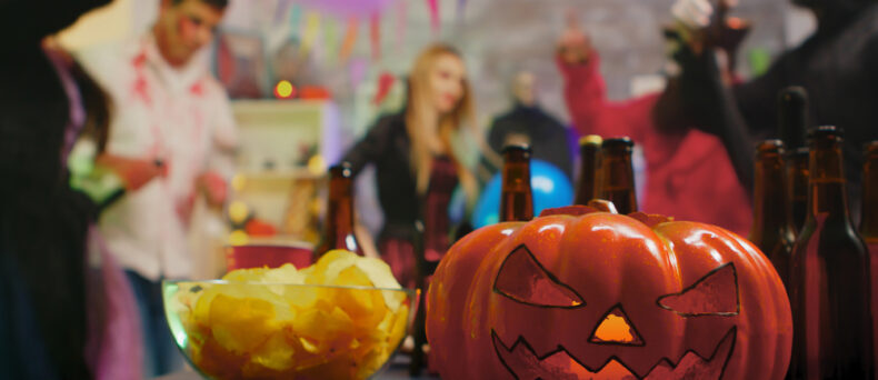 Scary pumpkin in forefront with halloween party in background