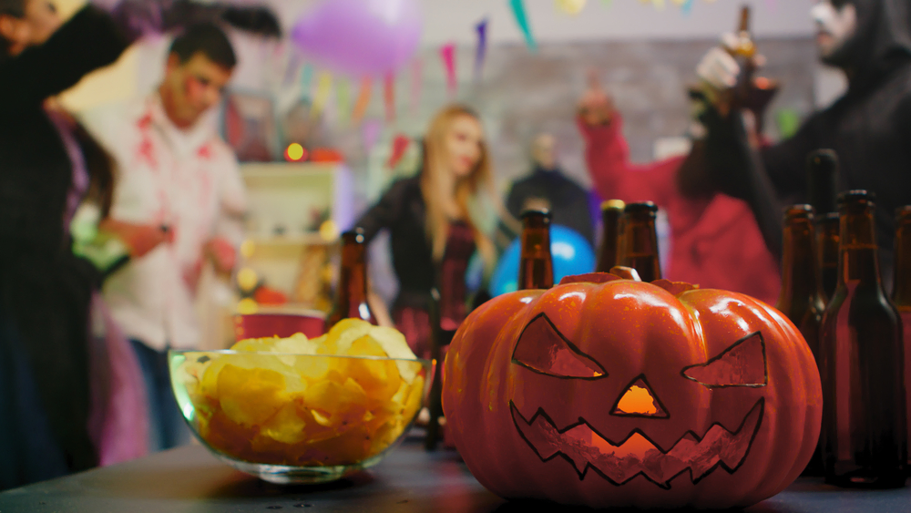 Scary pumpkin in forefront with halloween party in background