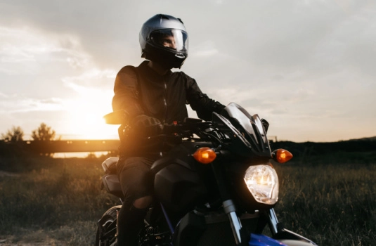motorcycle rider in silhouette with the setting sun behind him