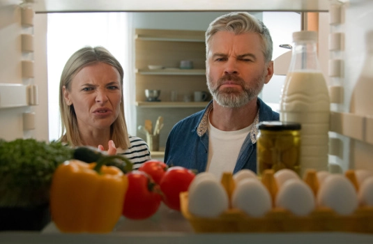 Couple looks inside fridge disgusted by smell of rotten food
