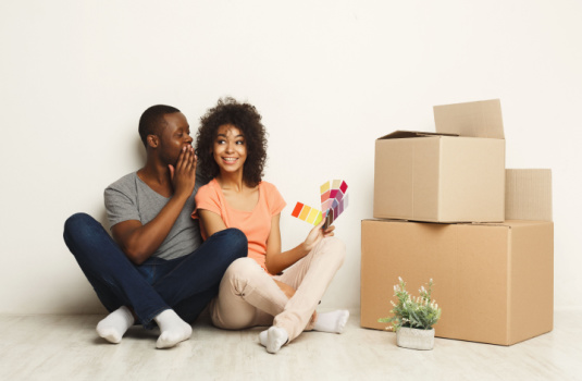 Happy African-American couple sits on floor of new home surrounded by moving boxes - home insurance in Georgia