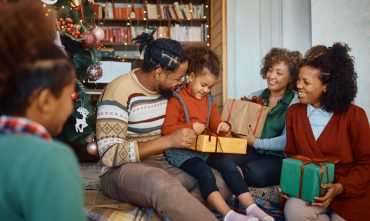 Happy African American multigeneration family enjoying in opening gifts on Christmas day at home.