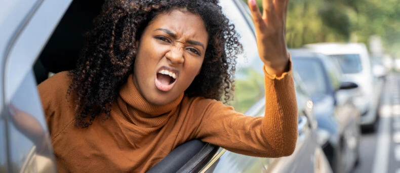 Angry young woman leans out driver's side window yelling - cheap car insurance in Georgia