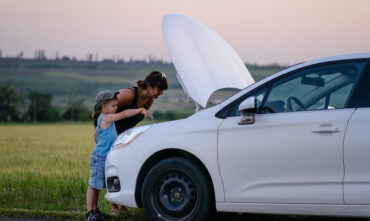 Mother and young son stand in front of car with hood up on side of the road - cheap roadside assistance in Georgia