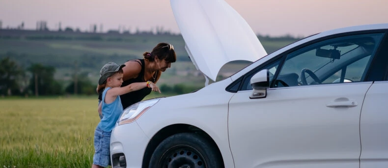 Mother and young son stand in front of car with hood up on side of the road - cheap roadside assistance in Georgia