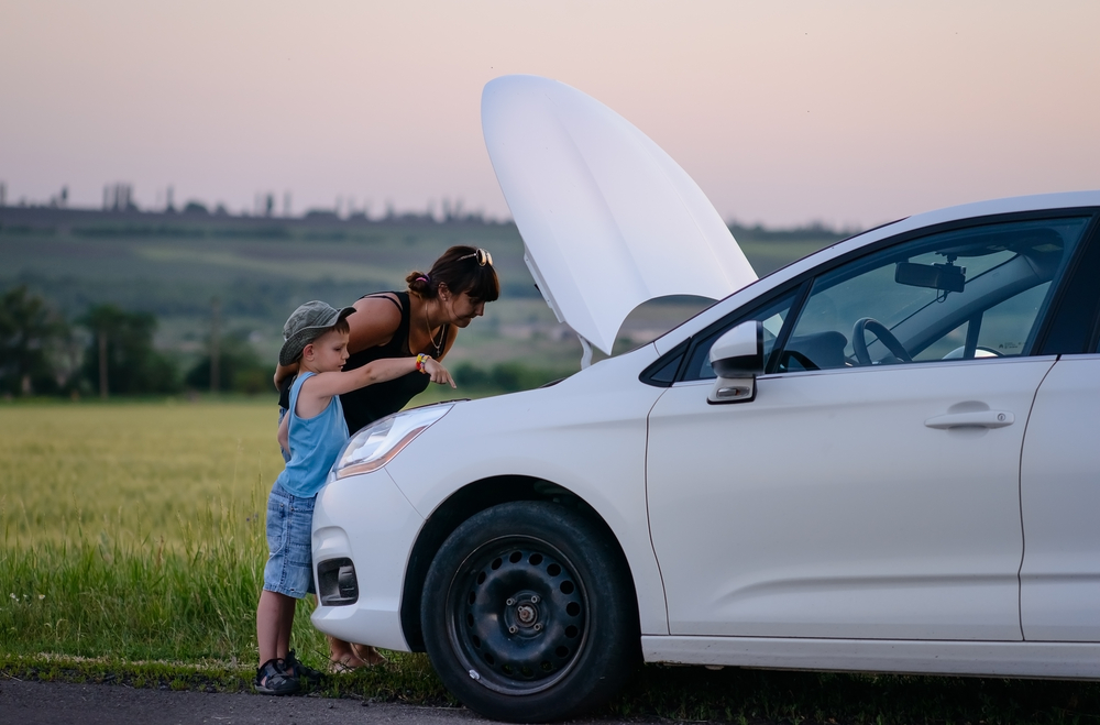 Mother and young son stand in front of car with hood up on side of the road - cheap roadside assistance in Georgia