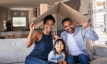 African-American couple holding a cardboard roof over them and their little girl concept of home insurance.