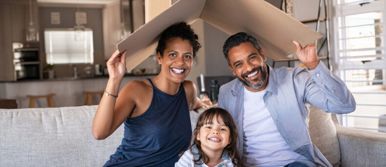 African-American couple holding a cardboard roof over them and their little girl concept of home insurance.