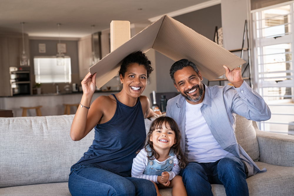African-American couple holding a cardboard roof over them and their little girl concept of home insurance.