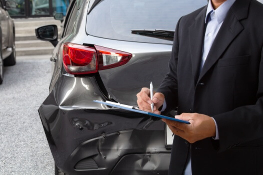 Insurance agent determines damage on a wrecked car.