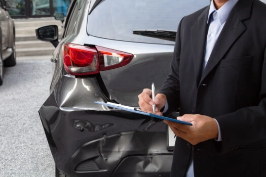 Insurance agent determines damage on a wrecked car.
