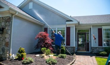 Homeowner power washes roof as part of home maintenance checklist - cheap home insurance in Georgia.