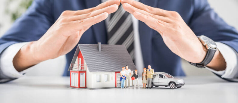 Insurance agent with hands over house, car and family, concept of bundling insurance for savings in Georgia.