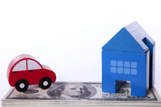 Red car and blue house sitting on top of money - saving money by bundling insurance in Georgia.