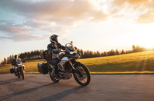Two motorcyclists ride touring bikes on an open road at sunset, illustrating freedom on two wheels and buy a motorcycle without a license.