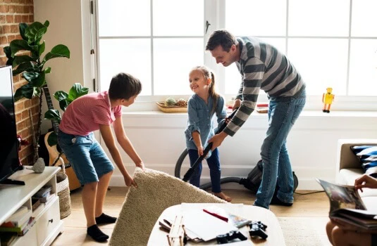 Dad and kids cleaning their house for the summer and smiling during the process.