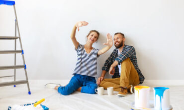 Couple sitting on the floor of their house imagining the renovations they will make - Southern Harvest Cheap homeowners in Georgia.