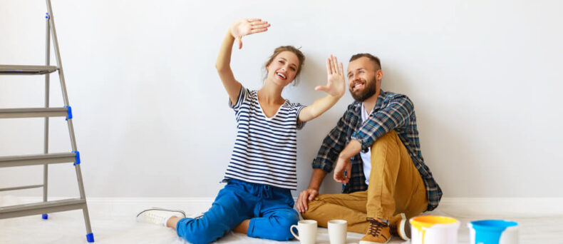 Couple sitting on the floor of their house imagining the renovations they will make - Southern Harvest Cheap homeowners in Georgia.