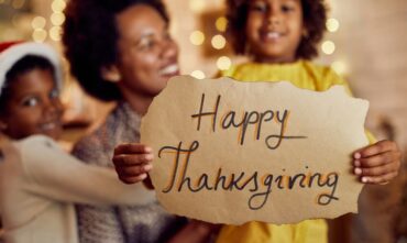 Mom with her son and daughter holding a happy thanksgiving sign.