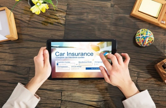 A picture of two female hands holding a small computer and looking at car insurance choices.