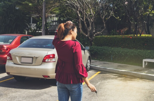 Woman stands looking at the empty parking space where her car was parked - cheap car insurance in Georgia.