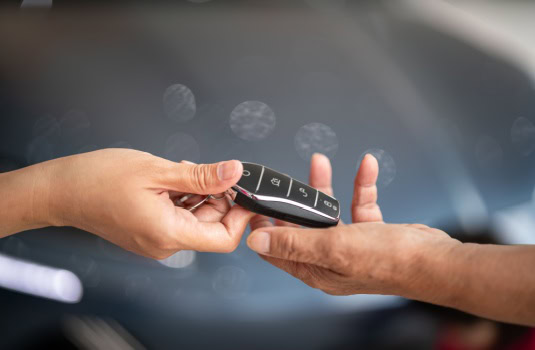 A hand is handing over a key to a car to another hand - cheap SR-22 insurance in Georgia.