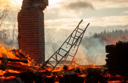 Image shows burned house with chimney and attic stairs - homeowners insurance in Georgia.