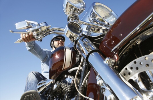 Motorcyclist on bike, wearing helmet, seen from below - cheap motorcycle insurance in Georgia.