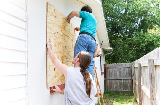 Father and son board windows up on the Georgia home before a hurricane - cheap home insurance.