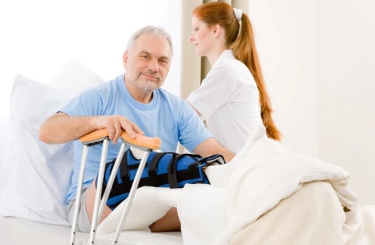 Man in cast in hospital bed with nurse after falling on someone's stairs - cheap renters insurance in Georgia.
