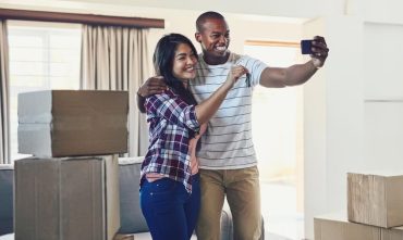 Happy couple, keys and selfie in new rental home for moving, rent in house with cheap renters insurance in Georgia.