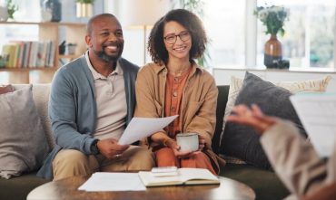 Insurance agent, meeting mature couple on sofa for estate planning, asset management or pension. Documents, life insurance and retirement paperwork with people at home for investment portfolio in Georgia.