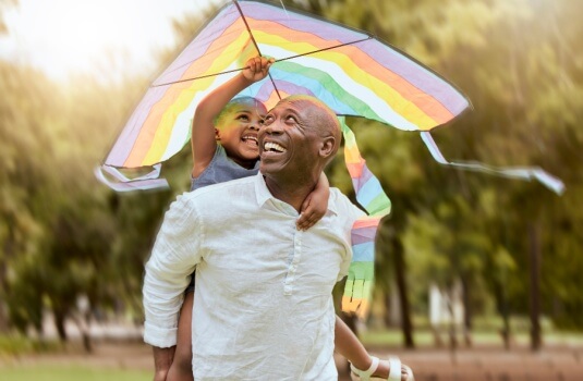 Father, child and rainbow kite outdoor at a nature park for fun, bonding and trust of life insurance and savings in Georgia.