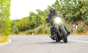 Motorcyclist riding toward the camera with headlight on, cheap motorcycle insurance in Georgia.