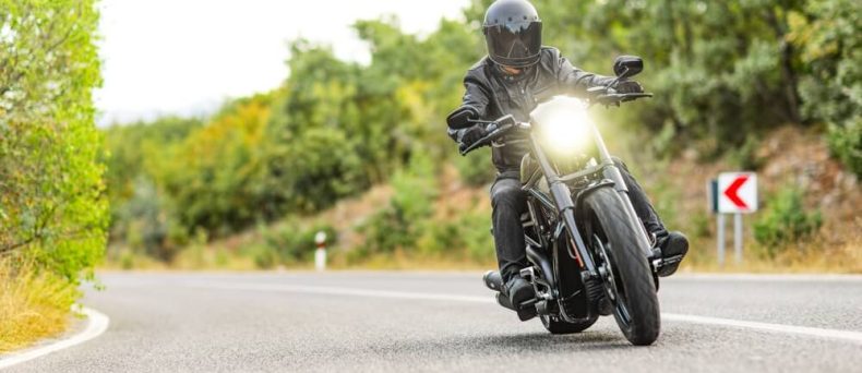 Motorcyclist riding toward the camera with headlight on, cheap motorcycle insurance in Georgia.