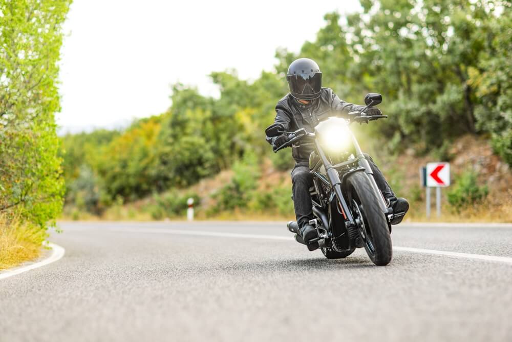 Motorcyclist riding toward the camera with headlight on, cheap motorcycle insurance in Georgia.