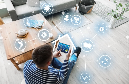 Man with tablet computer using application of smart home automation in room, getting cheaper home insurance through smart home technology.