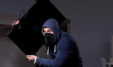Burglar thief stealing tv from apartment house, how to get help from renters insurance theft coverage.